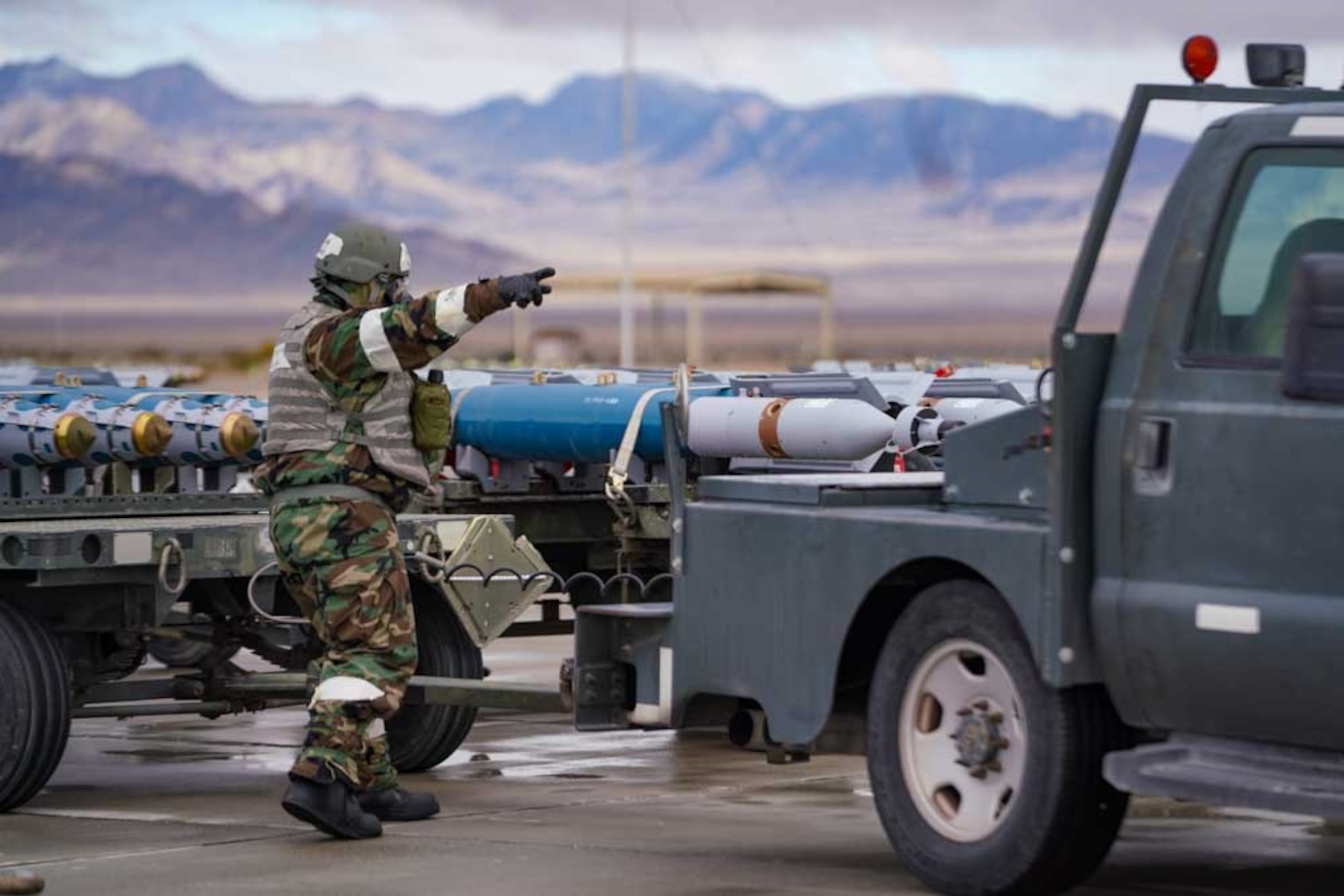 U.S. Air Force Senior Airman Alfred Rice, 25th Maintenance Squadron munitions support equipment maintenance crew chief, marshals a tow vehicle into position during exercise Iron Raven at Creech Air Force Base, Nevada, Nov. 19, 2025.