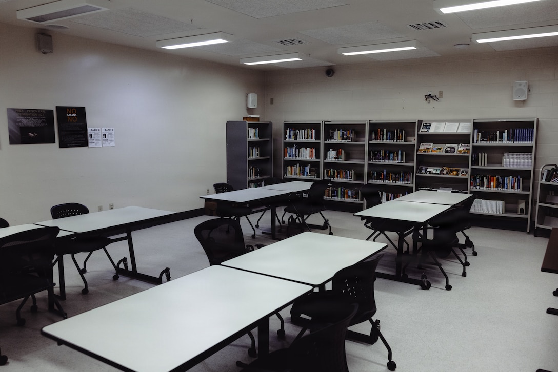 Tables and bookshelves are arranged inside the Marine Corps Installations East-Marine Corps Base (MCB) Camp Lejeune Regional Brig, MCB Camp Lejeune, Dec. 15, 2025. Multi‑purpose rooms in the brig are utilized for rehabilitation programs, including sexual assault prevention, anger management and Real Colors training. These classes support prisoners in better understanding their emotions, reflecting on past decisions and developing healthy strategies for processing those emotions. The multi‑purpose room also serves as the designated prisoner visitation area and houses a library. (U.S. Marine Corps photo by Cpl. Loriann Dauscher)