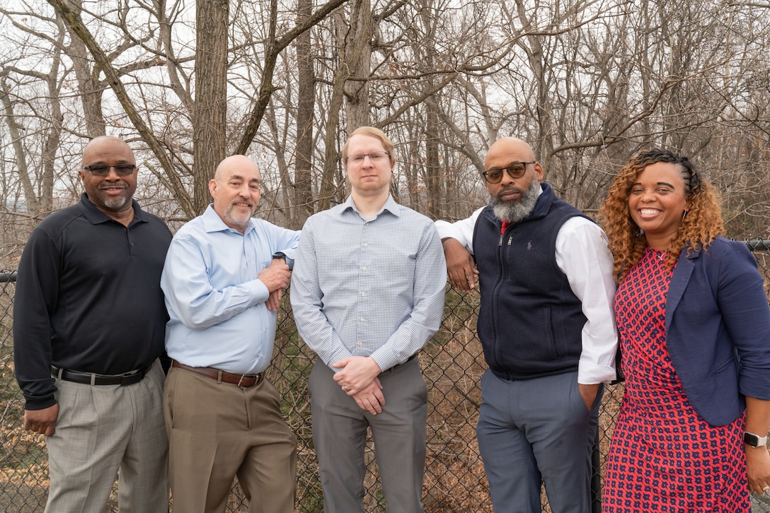 Five people standing in woods.