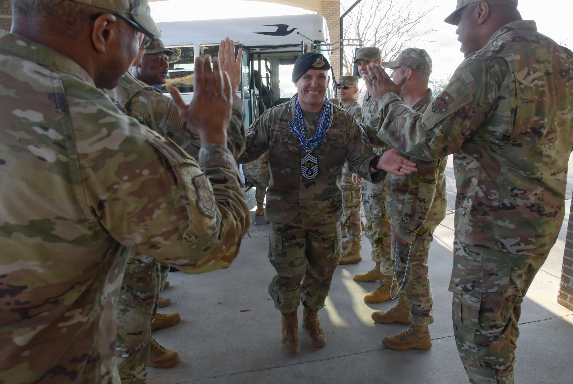 A person in military uniforms receives hi-fives from others in military uniforms.