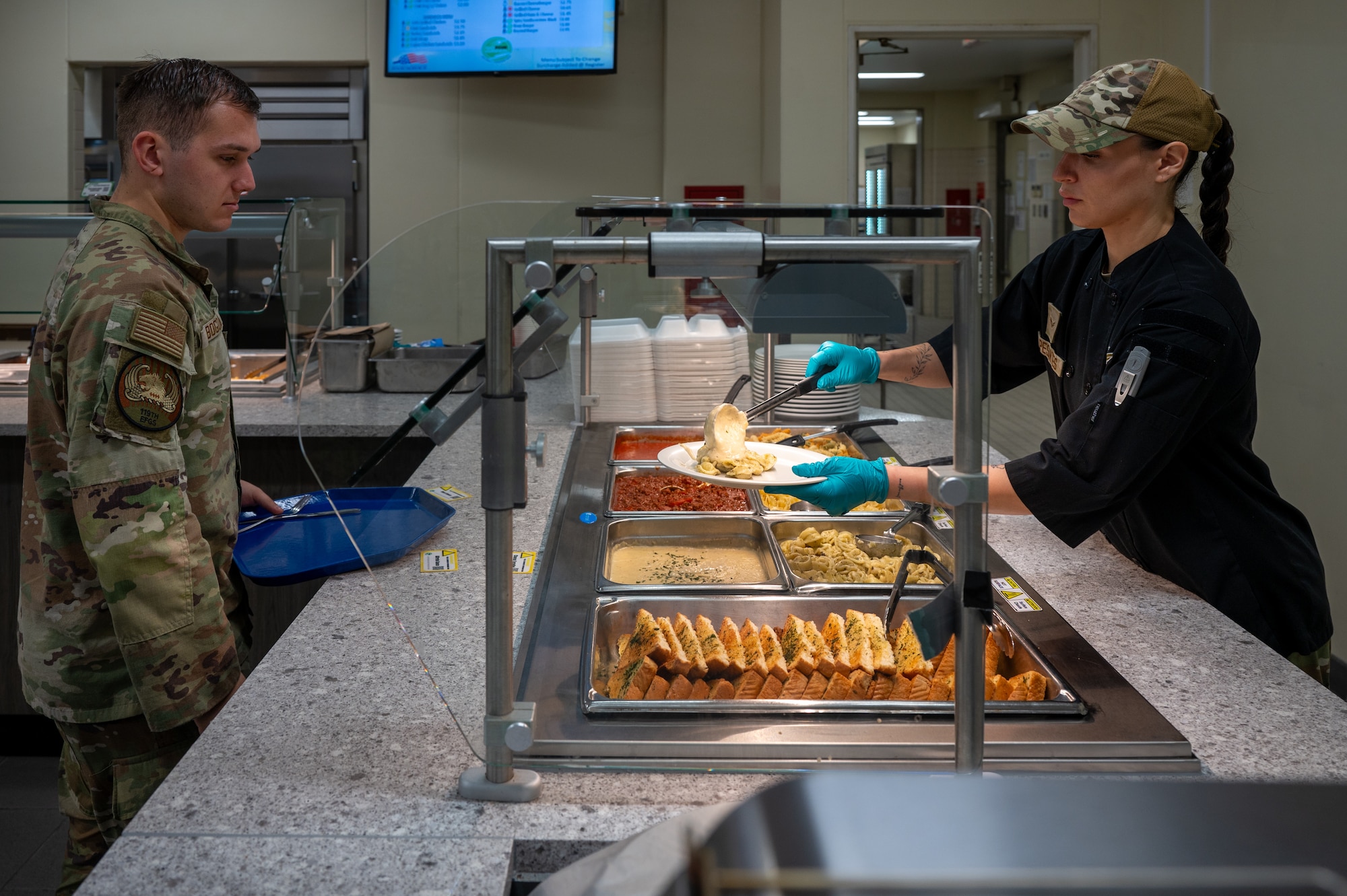 U.S. Air Force Airman 1st Class Jocelyne Pesantes, 718th Force Support Squadron food service member, serves an Airman at the Marshall Dining Facility specialty bar at Kadena Air Base, Japan, Jan 8, 2026. The 718th FSS food service team was named a finalist for the John L. Hennessy Award, recognizing excellence in Air Force food service operations. (U.S. Air Force photo by Airman 1st Class Francisco Huerta)