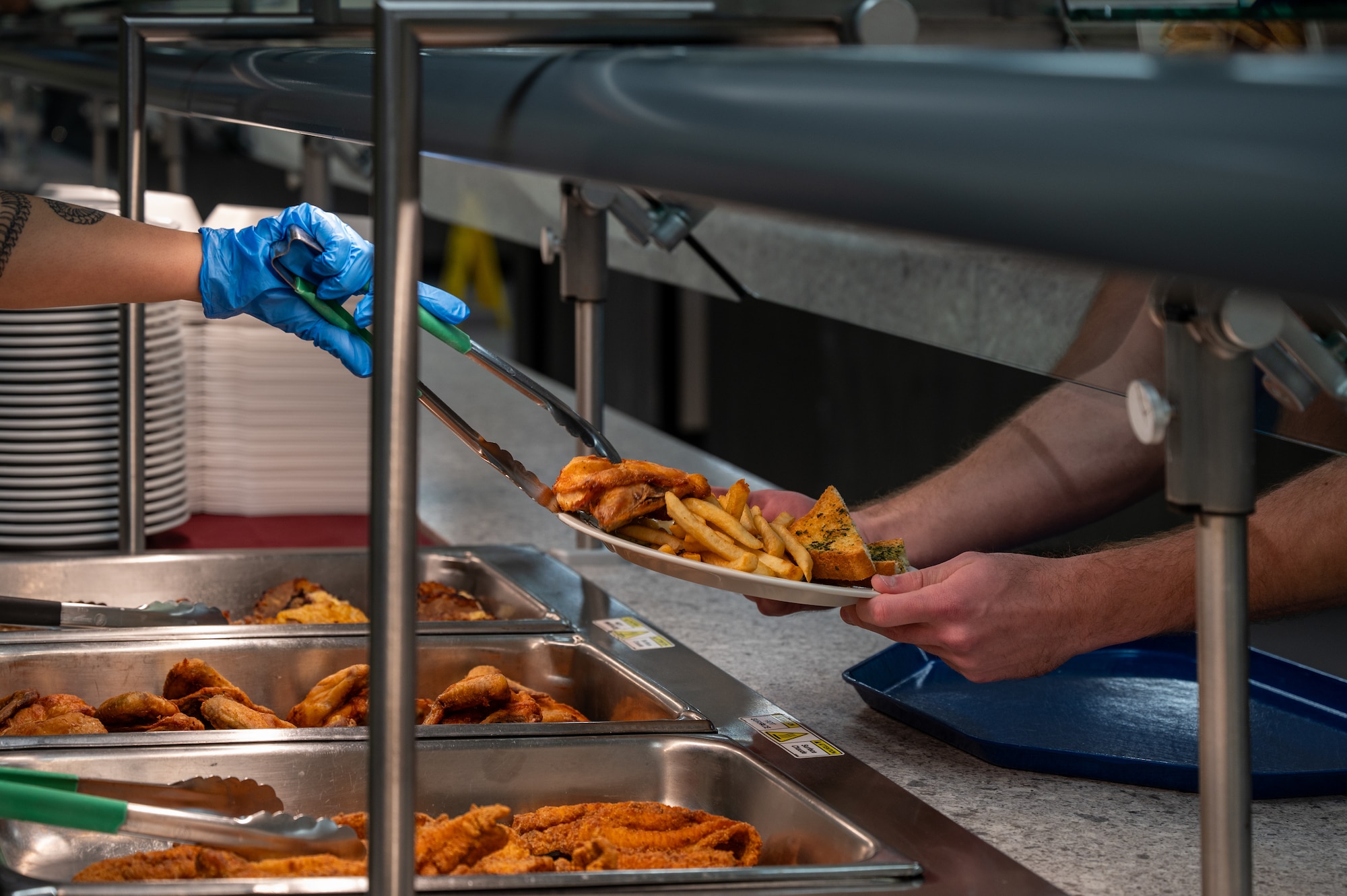 U.S. Air Force Airman 1st Class Itzel Cruz-Sanchez, 718th Force Support Squadron food service member, serves a meal at the Marshall Dining Facility at Kadena Air Base, Japan, Jan 8, 2026. The 718th FSS food service team was named a finalist for the John L. Hennessy Award, recognizing excellence in Air Force food service operations. (U.S. Air Force photo by Airman 1st Class Francisco Huerta)