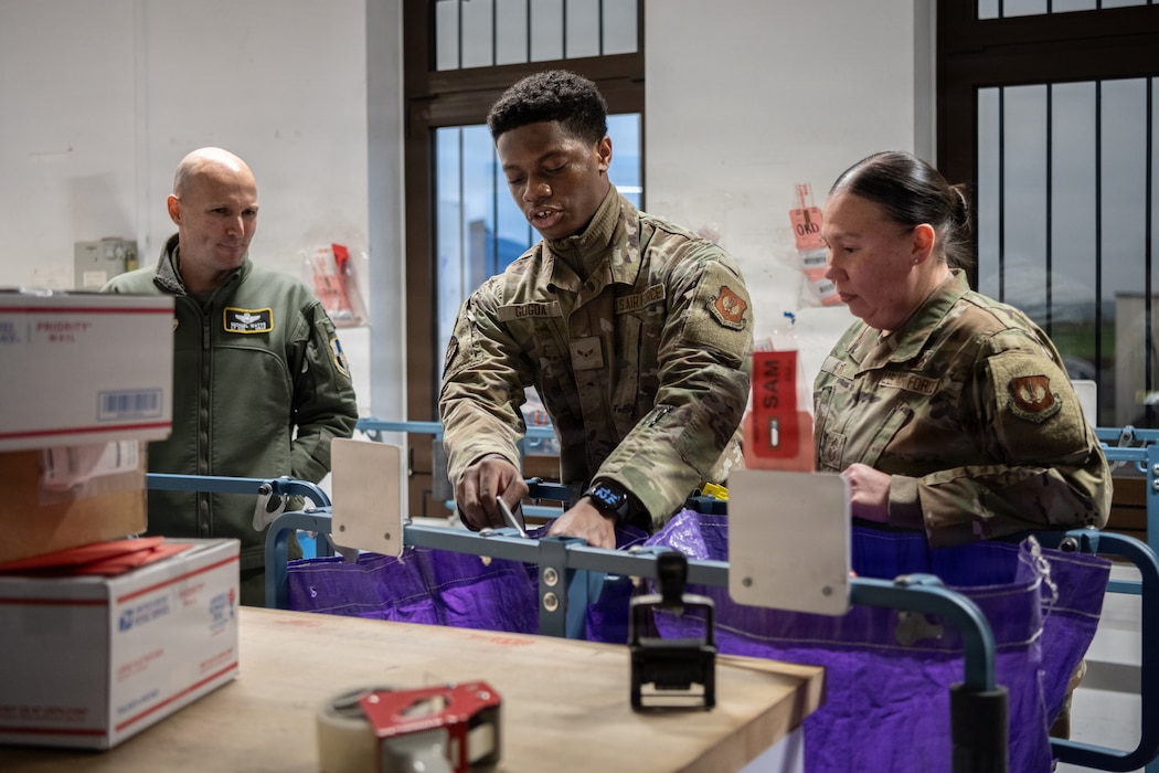Three U.S. Air Force Airmen set up mail bags.