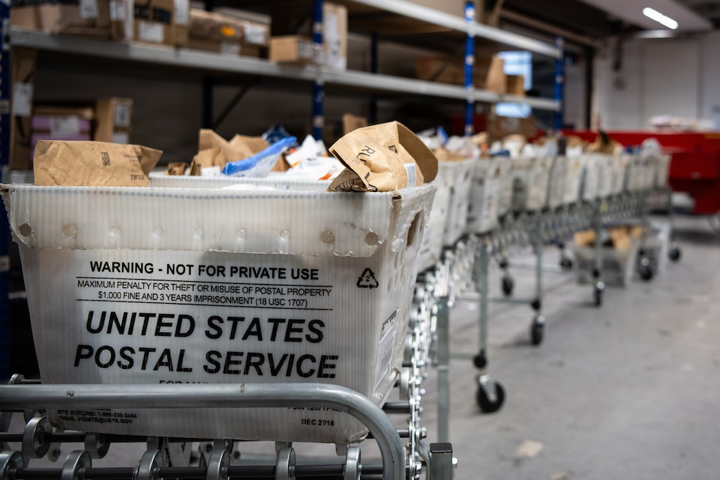Bins of mail sit on a roller conveyor.