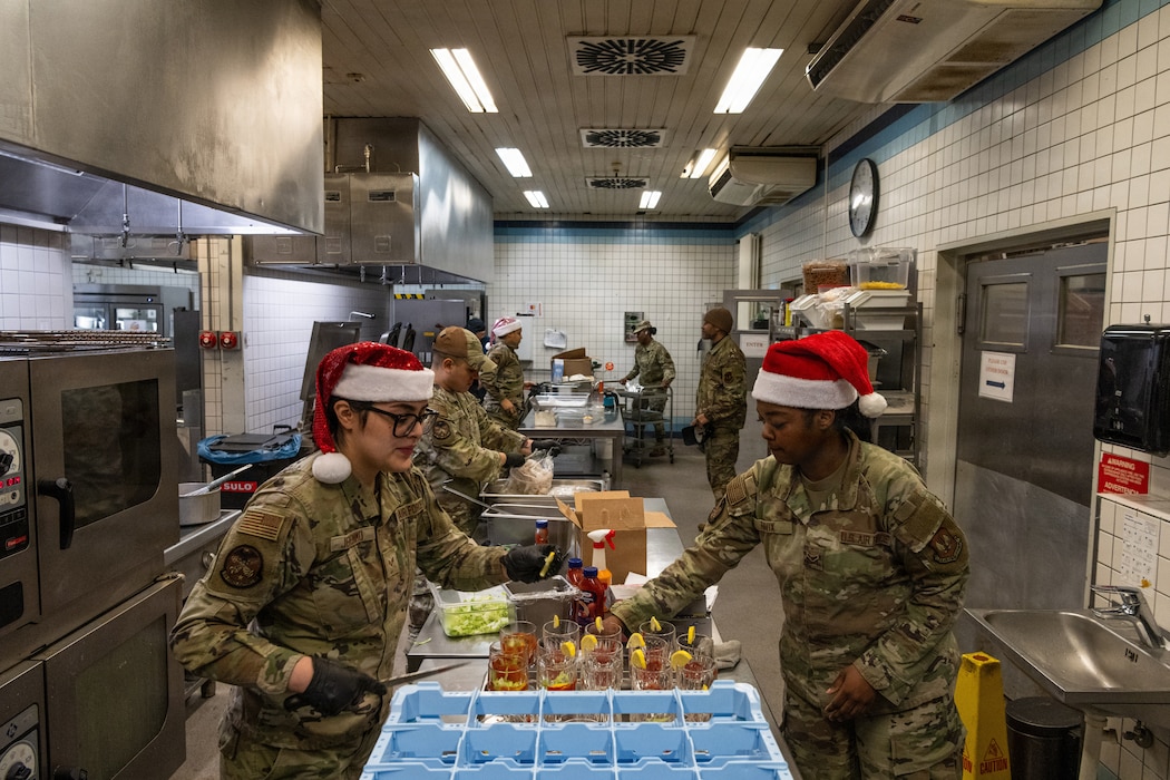 Several U.S. Air Force Airmen prepare food in a kitchen.