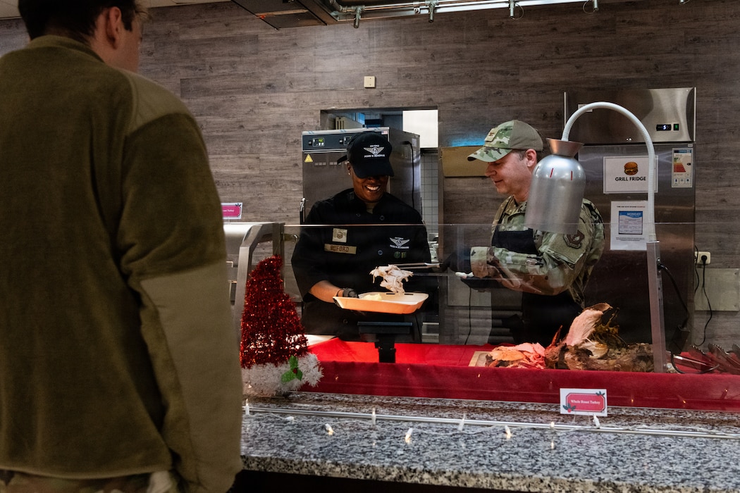 U.S. Air Force Airmen serve food in a buffet line.