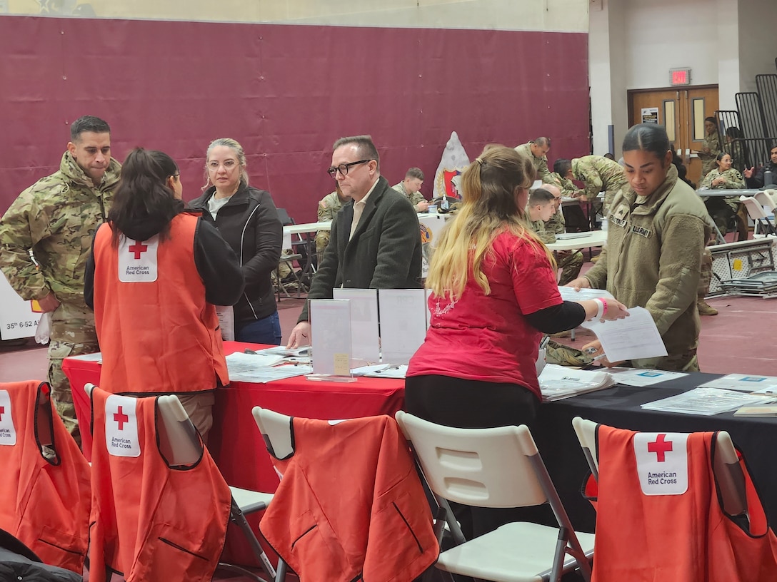 A series of people stand in front of a information verification table.