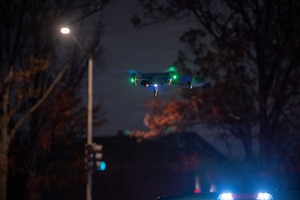 A small drone flies outside at night.