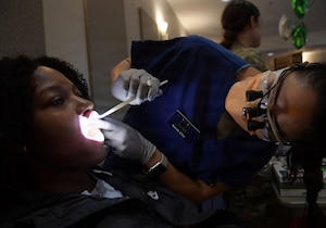 A dentist looks inside a woman's mouth for an oral screening.