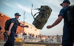 Coast Guard Academy cadets toss a seabag while disembarking the Coast Guard Cutter Eagle in Rockland, Maine, Aug. 3, 2024. The Eagle serves as a classroom at sea, giving all officers a foundation in seamanship and life underway. (U.S. Coast Guard photo by Petty Officer 3rd Class Matt Thieme)