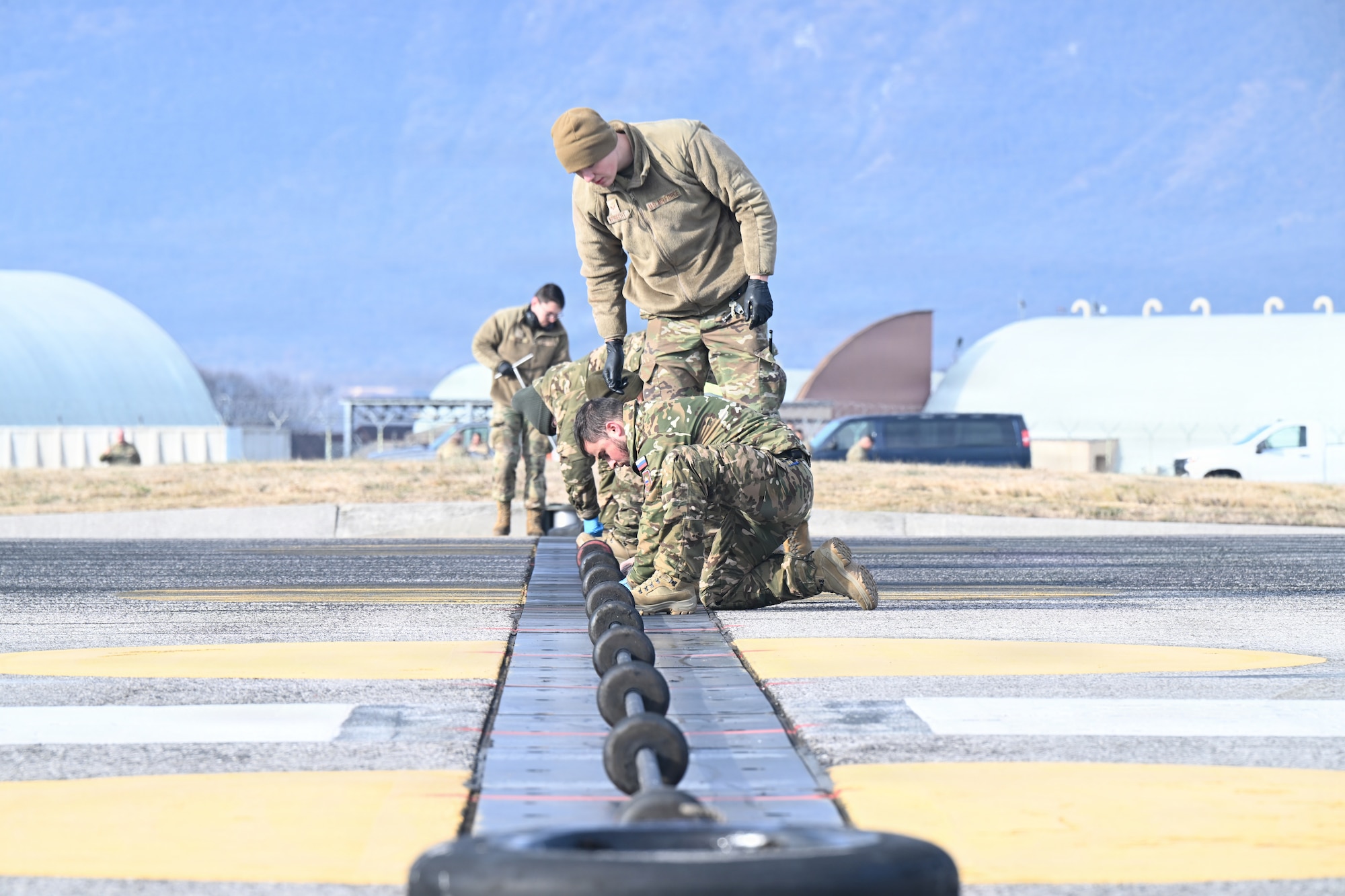 Service members inspects cables on the flightline.