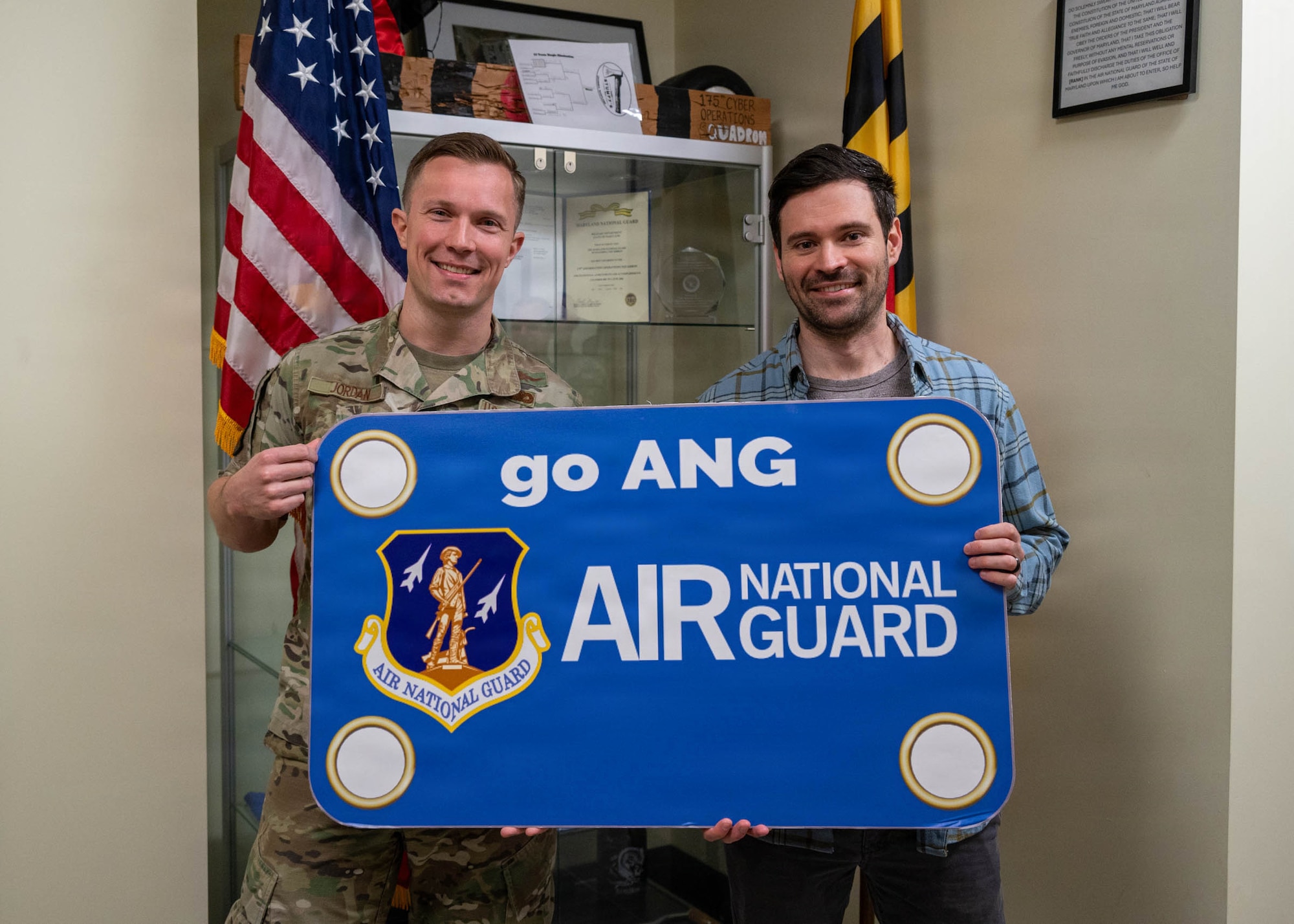 Maryland Air National Guard Maj. Paul Jordan, 175th Cyberspace Operations Squadron director of operations, and Chief Warrant Officer 2 Brian Ruzin, exploitation analyst for the 175th Cyberspace Operations Squadron, pose for a photo at Ruzin’s swearing-in ceremony at the Maryland Air National Guard Cyberspace Operations building on Fort George G. Meade, Maryland, December 19, 2025.