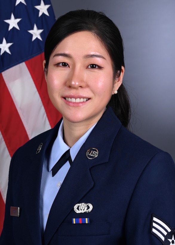 Official Photo of SrA Chloe Yoon in front of American Flag with service blues.