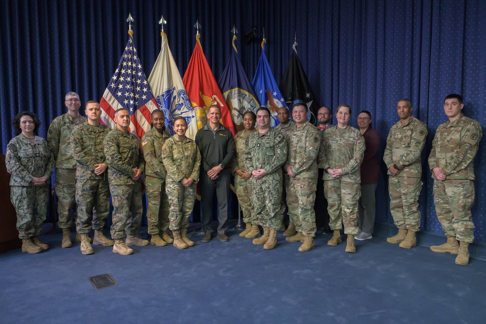 A group of Army soldiers and the former Sergeant Major of the Army stand in a group on a stage