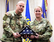 Col. Jeff Hicks, the Deputy United States Property and Fiscal Officer Army, presents Maj. Jennifer Hillyer with a framed American Flag during her retirement ceremony on Jan. 9.