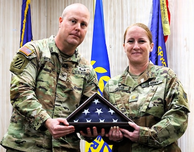 Col. Jeff Hicks, the Deputy United States Property and Fiscal Officer Army, presents Maj. Jennifer Hillyer with a framed American Flag during her retirement ceremony on Jan. 9.