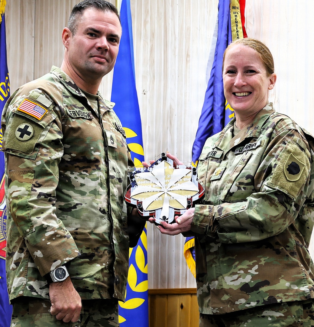 Illinois Army National Guard Sgt. 1st Class Michael Servough presents a gift to Maj. Jennifer Hillyer on behalf of the soldiers she served with during her retirement ceremony on Jan. 9.