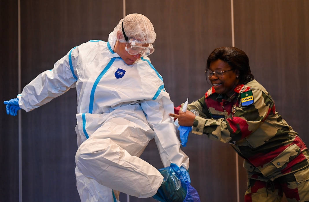 U.S. Army Col. Kelley Togiola, U.S. Army Southern European Task Force Africa, left, receives help from Gabon Armed Forces Col Mbongo-Kama, Gabonese Army Health Services clinical pathologist, during a hands-on session focusing on donning and doffing personal protective equipment during the African Partner Outbreak Response Alliance 2025 Workshop in Rabat, Morocco, Dec. 12, 2025. One key focus area during APORA 2025 was furthering efforts to strengthen coordination between military and civil organizations during a disease outbreak. (U.S. Air Force photo by Capt. Benjamin Aronson)