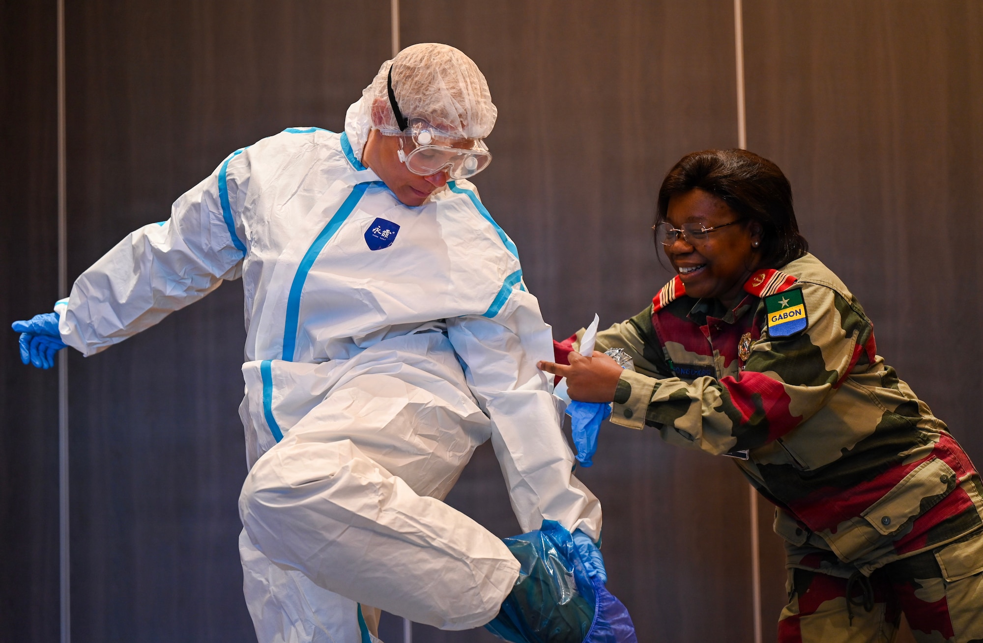 U.S. Army Col. Kelley Togiola, U.S. Army Southern European Task Force Africa, left, receives help from Gabon Armed Forces Col Mbongo-Kama, Gabonese Army Health Services clinical pathologist, during a hands-on session focusing on donning and doffing personal protective equipment during the African Partner Outbreak Response Alliance 2025 Workshop in Rabat, Morocco, Dec. 12, 2025. One key focus area during APORA 2025 was furthering efforts to strengthen coordination between military and civil organizations during a disease outbreak. (U.S. Air Force photo by Capt. Benjamin Aronson)
