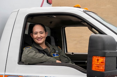 Uniformed service member smiles in passenger seat of truck.