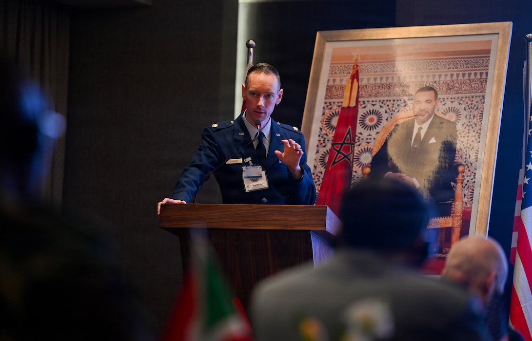 U.S. Air Force Maj. John Kieffer, U.S. Air Forces in Europe - Air Forces Africa command surgeon international health specialist, briefs on the objectives of the African Partner Outbreak Response Alliance 2025 Workshop in Rabat, Morocco, December 8, 2025. APORA 2025 aimed to enhance cross-collaboration between African nations on best practices and health crisis capabilities to prevent, mitigate and respond to disease outbreaks. (U.S. Air Force photo by Capt. Benjamin Aronson) (This photo was altered for security purposes by blurring a security badge.)