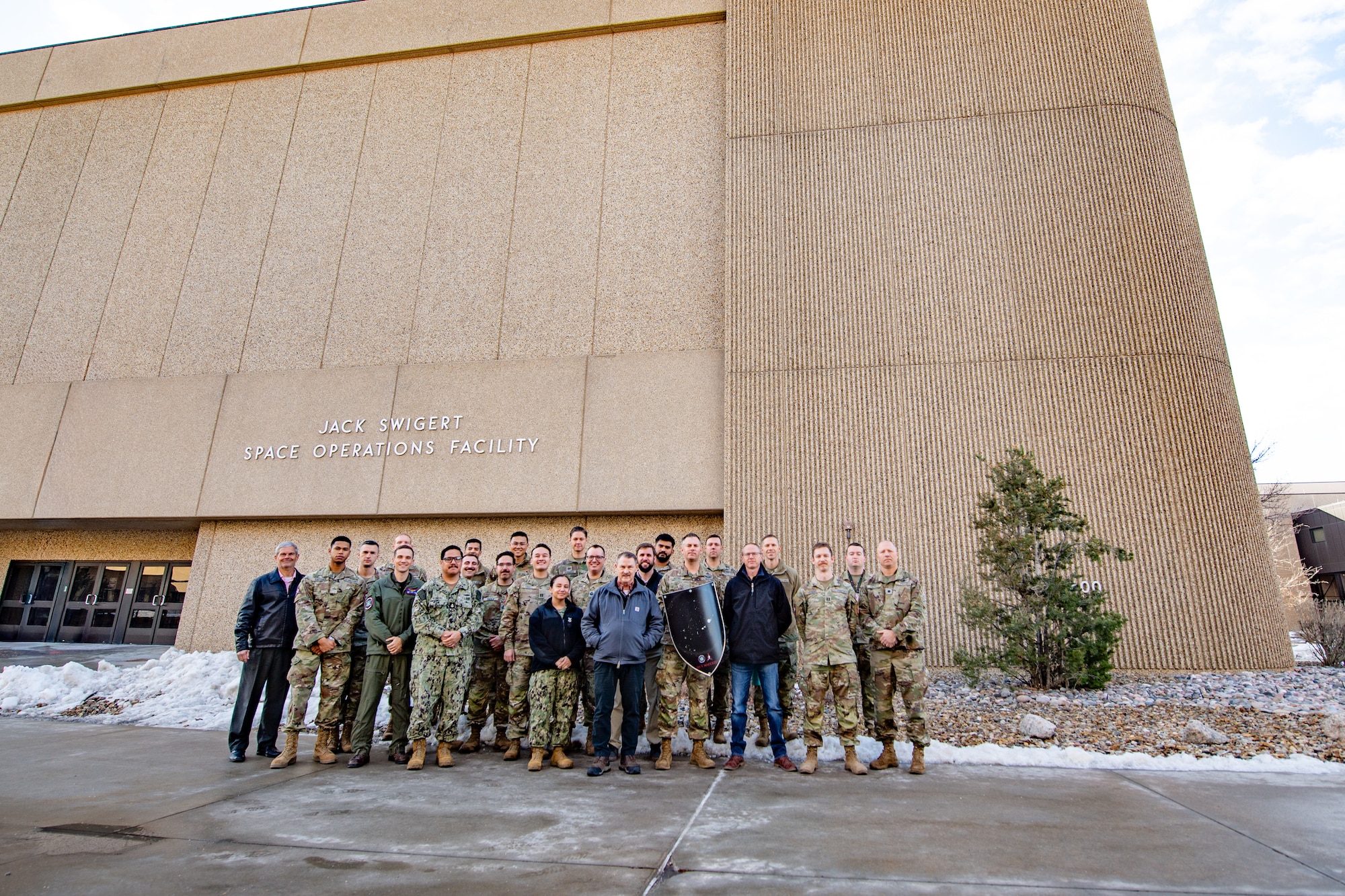 A group of people stand together outside of a large building in various military uniforms