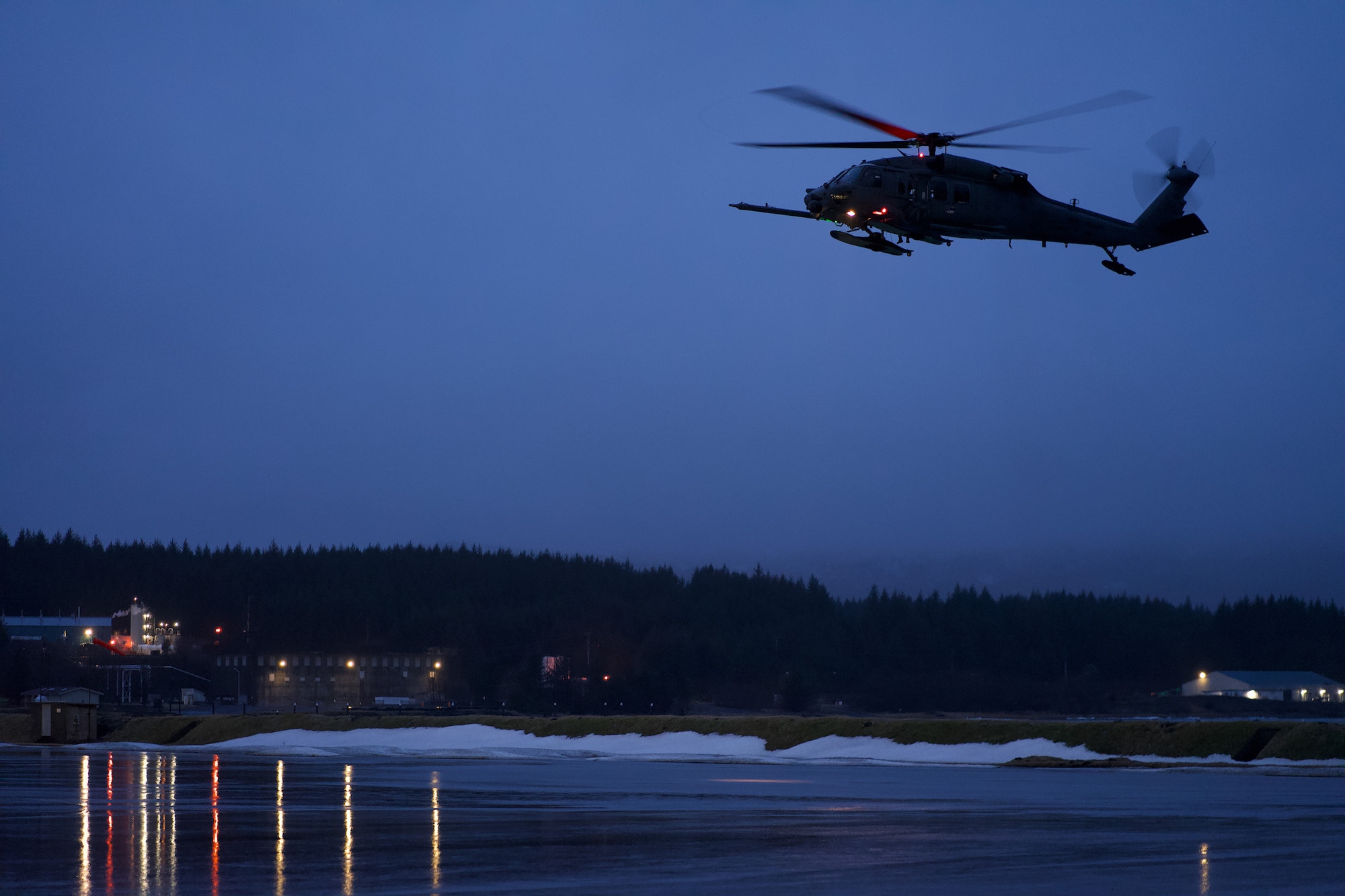 Carrying U.S. Coast Guard members of the Maritime Security Response Team, a 210th Rescue Squadron HH-60G Pave Hawk combat search and rescue helicopter conducts joint hoist training Jan. 23, 2023, at Coast Guard Station Kodiak.