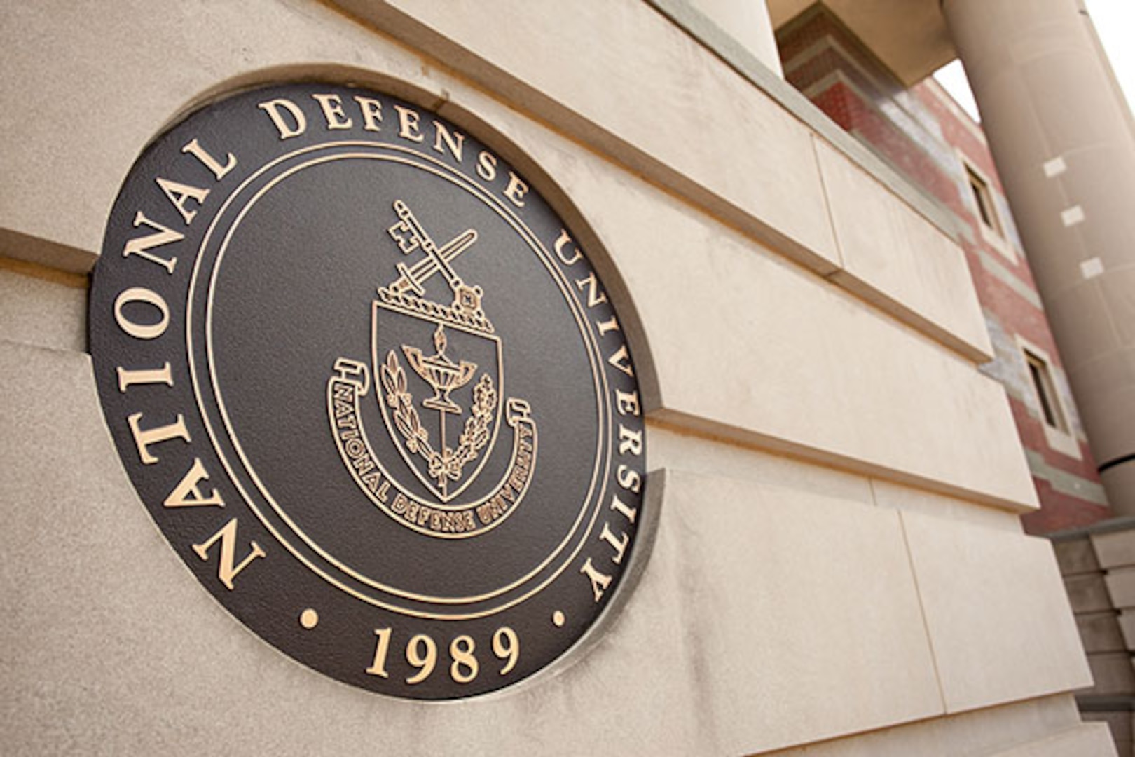 The National Defense's University seal on the side of a building