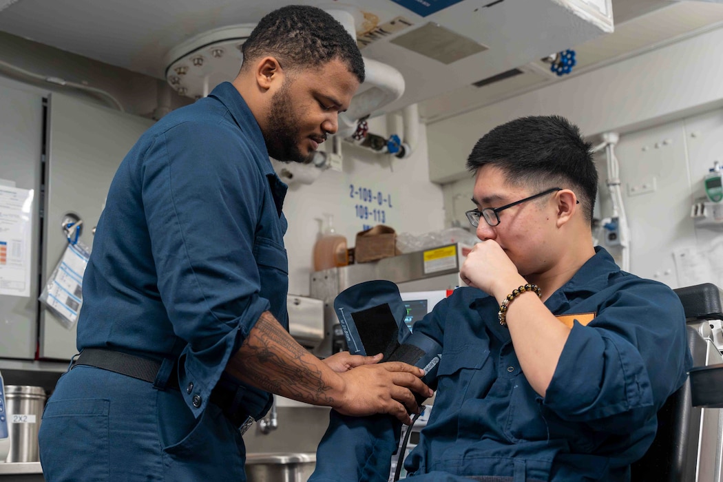 U.S. Navy Hospitalman Daimell O’Donnell, left, takes vitals on U.S. Navy Operations Specialist Seaman Mitch Tan aboard Nimitz-class aircraft carrier USS Abraham Lincoln (CVN 72) on Jan. 1, 2026. The Abraham Lincoln Carrier Strike Group is underway conducting routine operations in the U.S. 7th Fleet area of operations. Units assigned to 7th Fleet conduct regular Indo-Pacific patrols to deter aggression, strengthen alliances and partnerships, and advance peace through strength. (U.S. Navy photo by Mass Communication Specialist Seaman Angel Campbell)