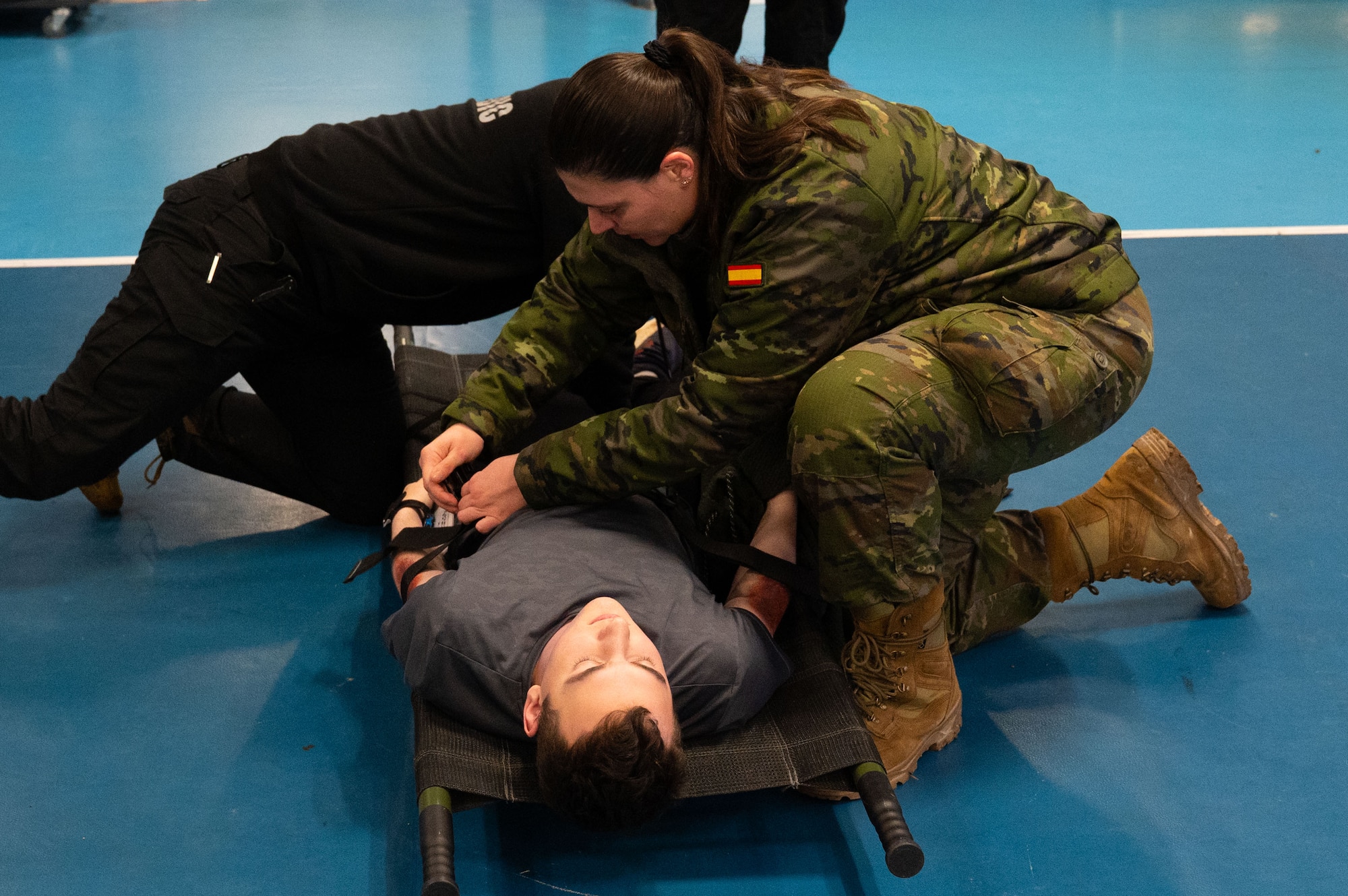 Spanish soldiers prepare simulated victim for transport.