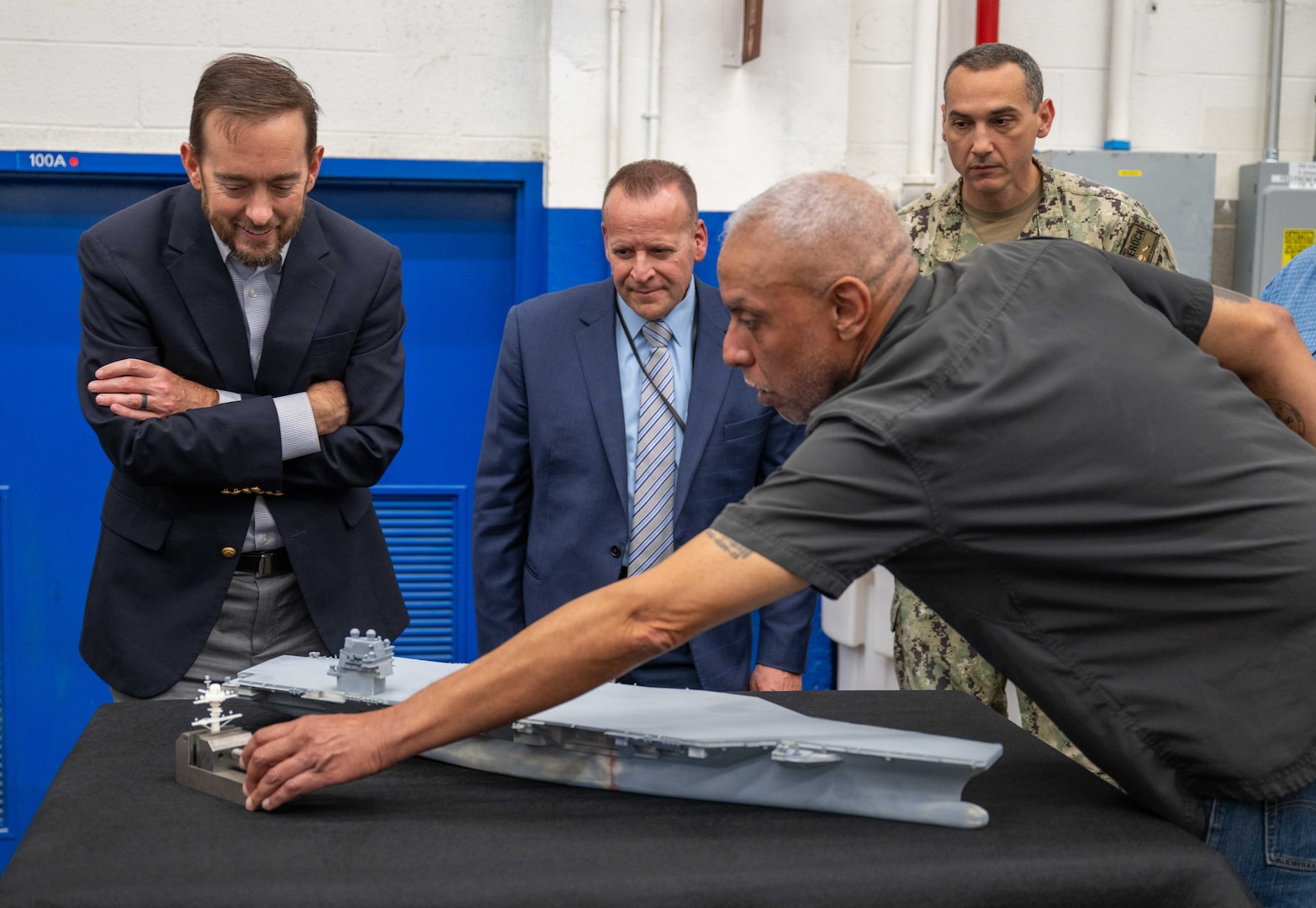 Mr. Alexis Colon, an employee with the Fabrication and Technical Support Division, explains to visitors how the team's equipment is able to deliver meticulous detail when assembling models for the U.S. Navy at Naval Surface Warfare Center, Carderock Division in West Bethesda on Aug. 28, 2025. Pictured from left are: Mr. Chris Miller, Executive Director of Naval Sea Systems Command; Mr. Tom Perotti, Executive Director, Naval Sea Systems Command, Engineering and Logistics (SEA 05), and (Acting) Executive Director Naval Surface and Undersea Warfare Centers; and Capt. Chris Matassa, Carderock's Commanding Officer.