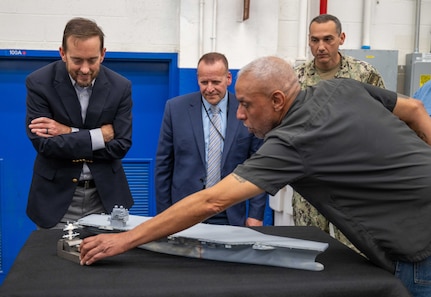 Mr. Alexis Colon, an employee with the Fabrication and Technical Support Division, explains to visitors how the team's equipment is able to deliver meticulous detail when assembling models for the U.S. Navy at Naval Surface Warfare Center, Carderock Division in West Bethesda on Aug. 28, 2025. Pictured from left are: Mr. Chris Miller, Executive Director of Naval Sea Systems Command; Mr. Tom Perotti, Executive Director, Naval Sea Systems Command, Engineering and Logistics (SEA 05), and (Acting) Executive Director Naval Surface and Undersea Warfare Centers; and Capt. Chris Matassa, Carderock's Commanding Officer.