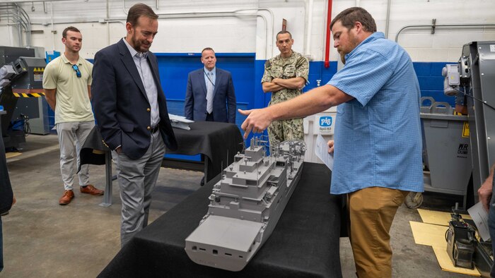 Mr. Adam Smith (right), an employee with the Fabrication and Technical Support Division, explains the assembly of the physical models to visitors at Naval Surface Warfare Center, Carderock Division in West Bethesda on Aug. 28, 2025. Pictured from left are: Mr. Matt Gutmann; Mr. Chris Miller, Executive Director of Naval Sea Systems Command; Mr. Tom Perotti, Executive Director, Naval Sea Systems Command, Engineering and Logistics (SEA 05), and (Acting) Executive Director Naval Surface and Undersea Warfare Centers; and Capt. Chris Matassa, Carderock's Commanding Officer.