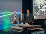 Carderock’s Jeremy Salmon, Alexis Colon and Adam Smith, all from Naval Surface Warfare Center Carderock Division’s Additive and Subtractive Shop (Code 621), stand with two of the models they created at the Surface Navy Association National Symposium in Arlington, Va., on Jan. 13, 2026.