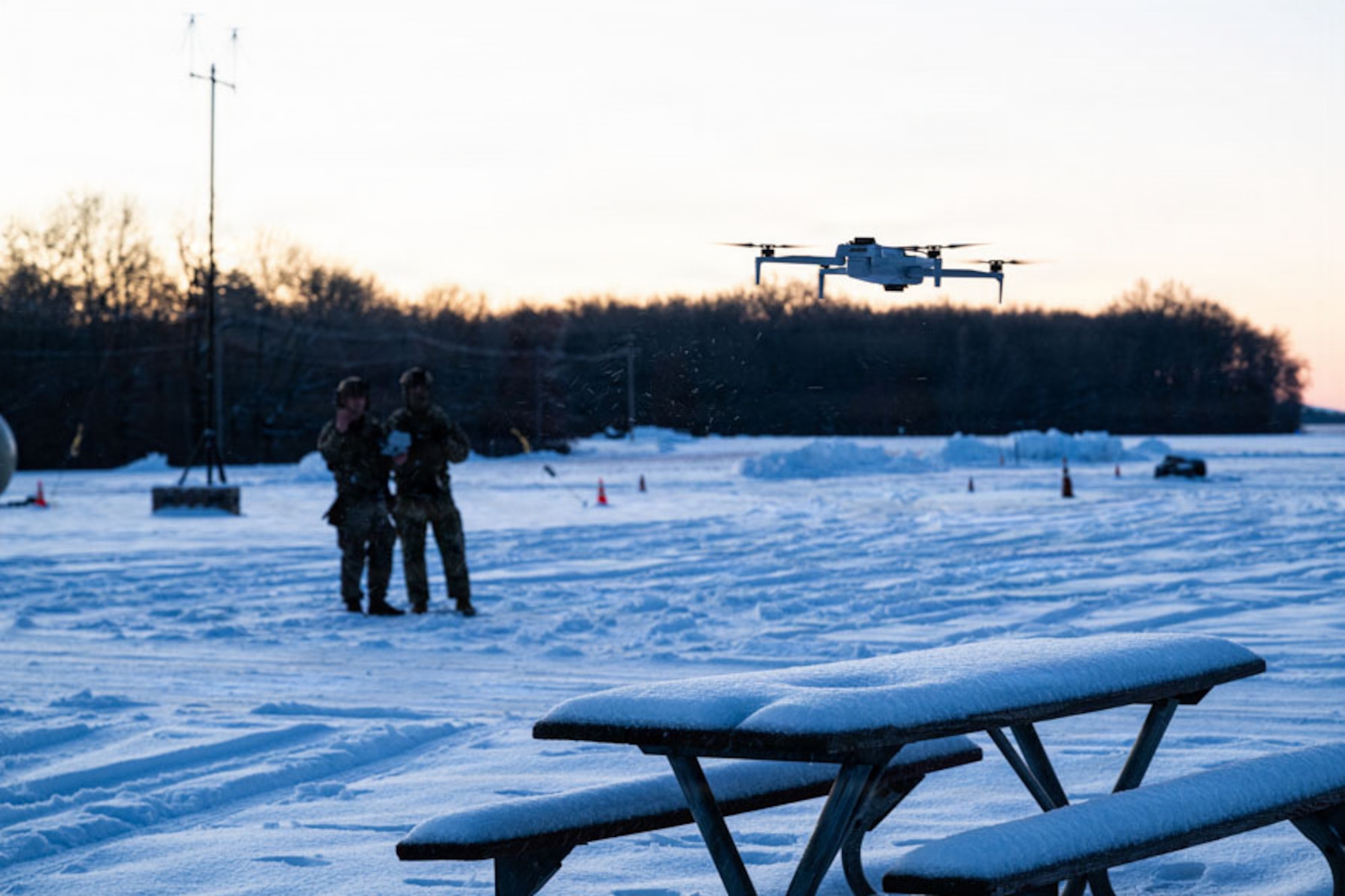 Two Airmen observe a small unmanned aerial vehicle.