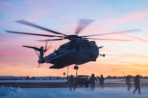 A helicopter hovers over Airmen.