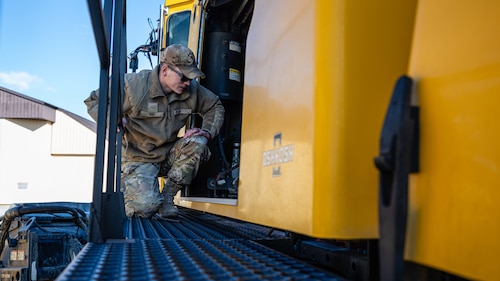 Airmen inspect snow removal equipment.