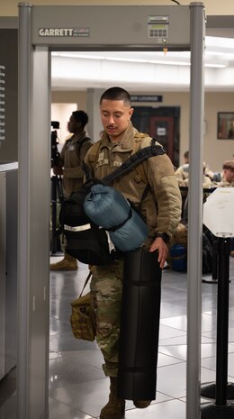 A U.S. Air Force Airman passes through a metal detector as he prepares to board a bus.