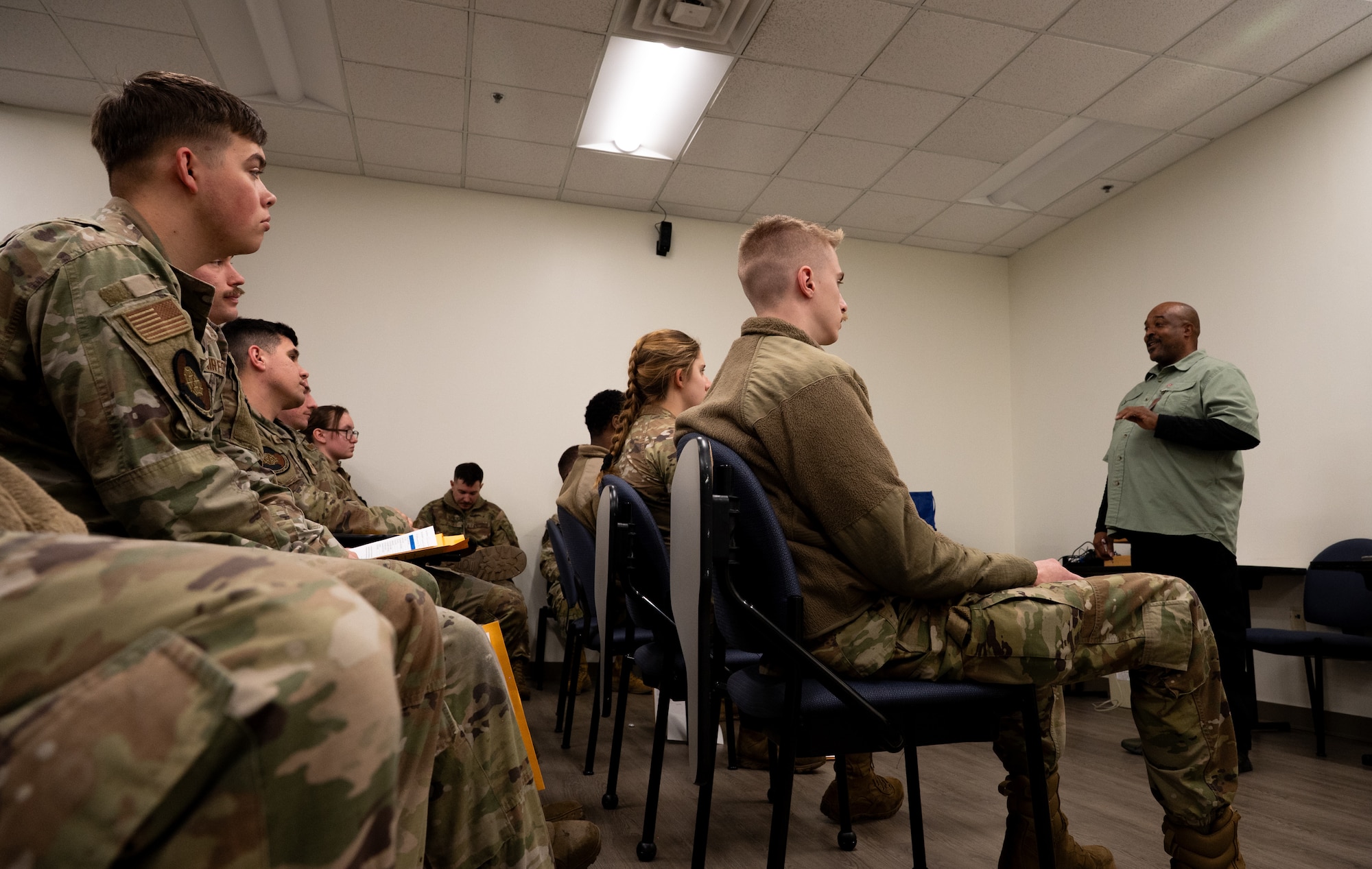 A black male public health specialist gives a brief to a room of U.S. Air Force Airman.