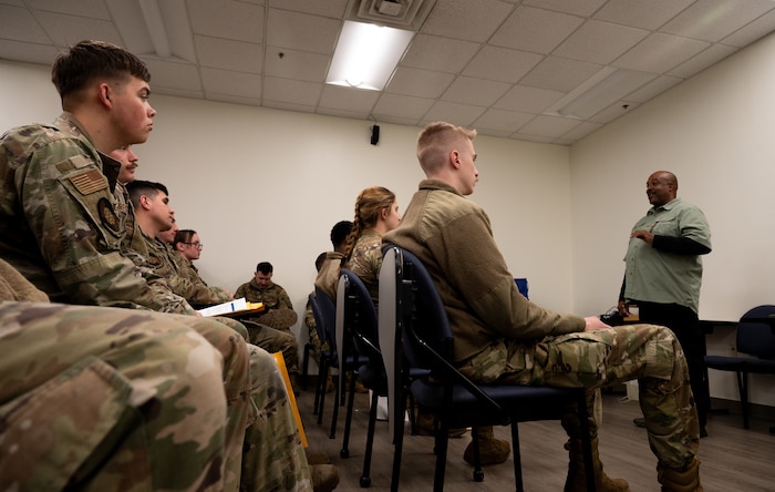 A black male public health specialist gives a brief to a room of U.S. Air Force Airman.