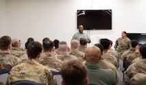A black male public health specialist gives a brief to a room of U.S. Air Force Airman.