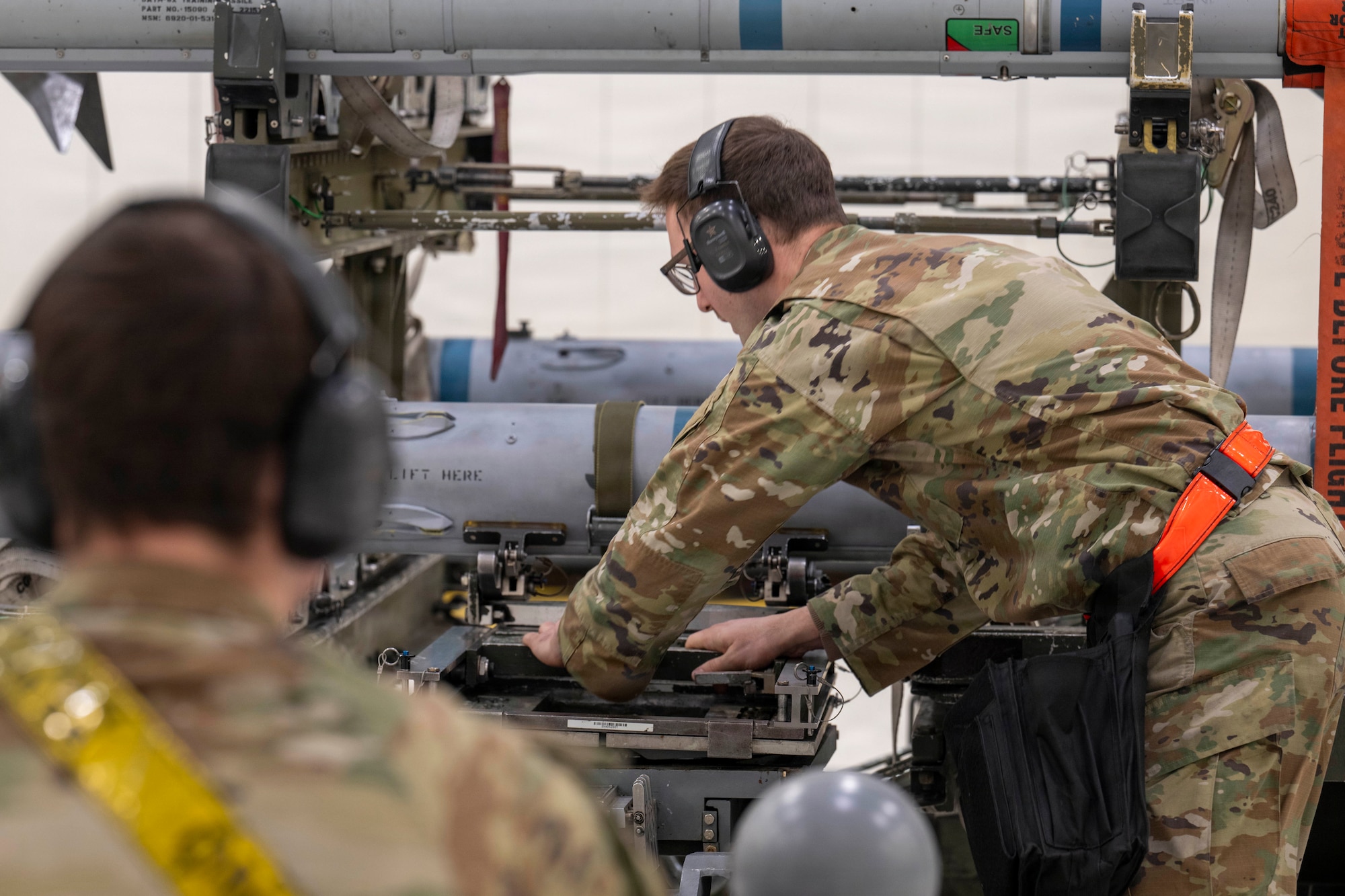 U.S. Air Force Senior Airman Peyton Morris, 18th Fighter Generation Squadron weapons load crew member, left, and Staff Sgt. Cody Fowler, 18th FGS weapons load crew chief, secure a dummy CATM-120B missile onto an MJ-1B load truck during the 4th Quarter Load Competition at Eielson Air Force Base, Alaska, Jan. 9, 2026.