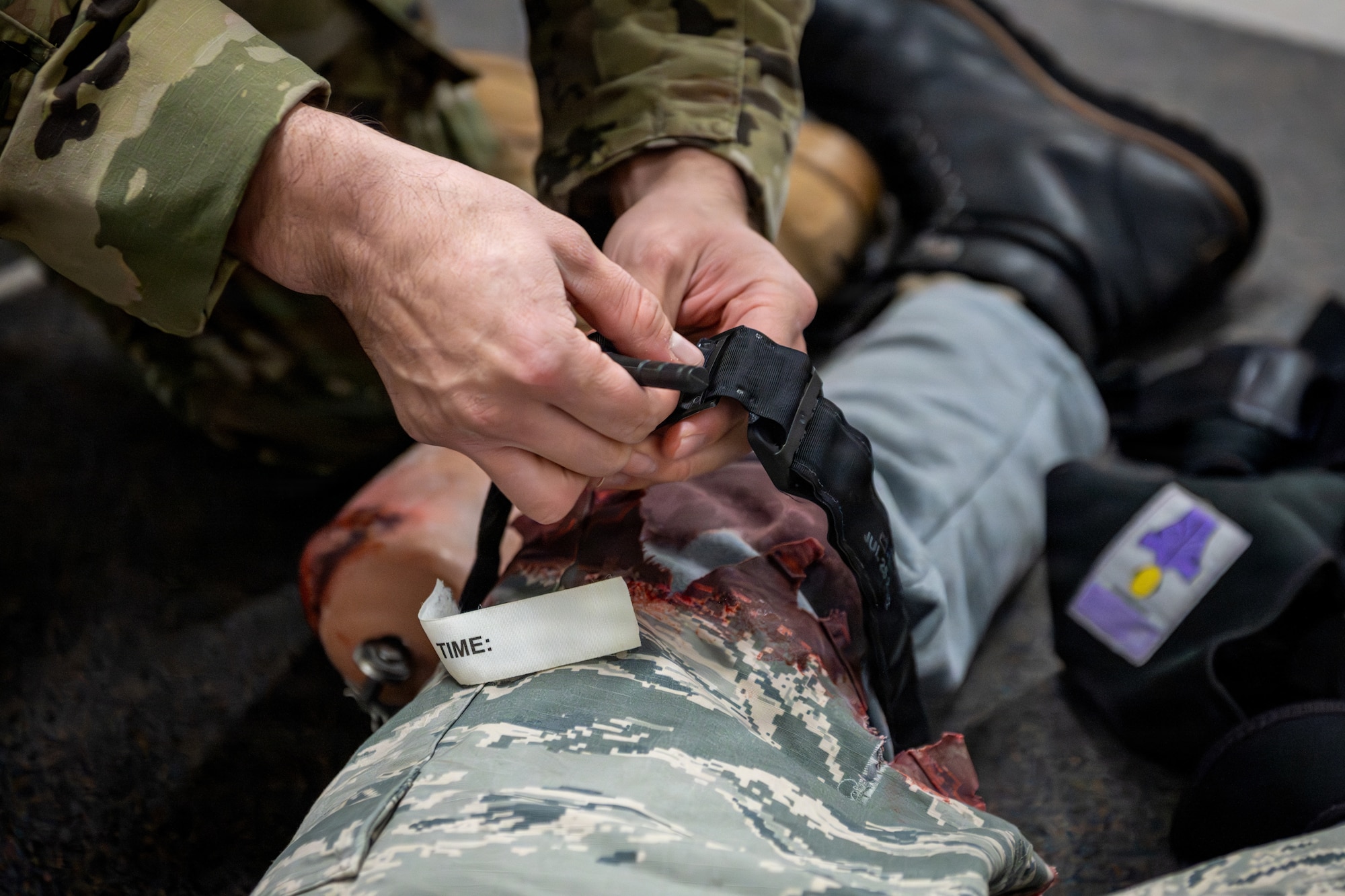 U.S. Air Force Tech. Sgt. Brandon Sanchez, 35th Comptroller Squadron noncommissioned officer in charge of financial analysis, applies a tourniquet on a simulated patient as part of a mass casualty exercise during Sprint 26-2.