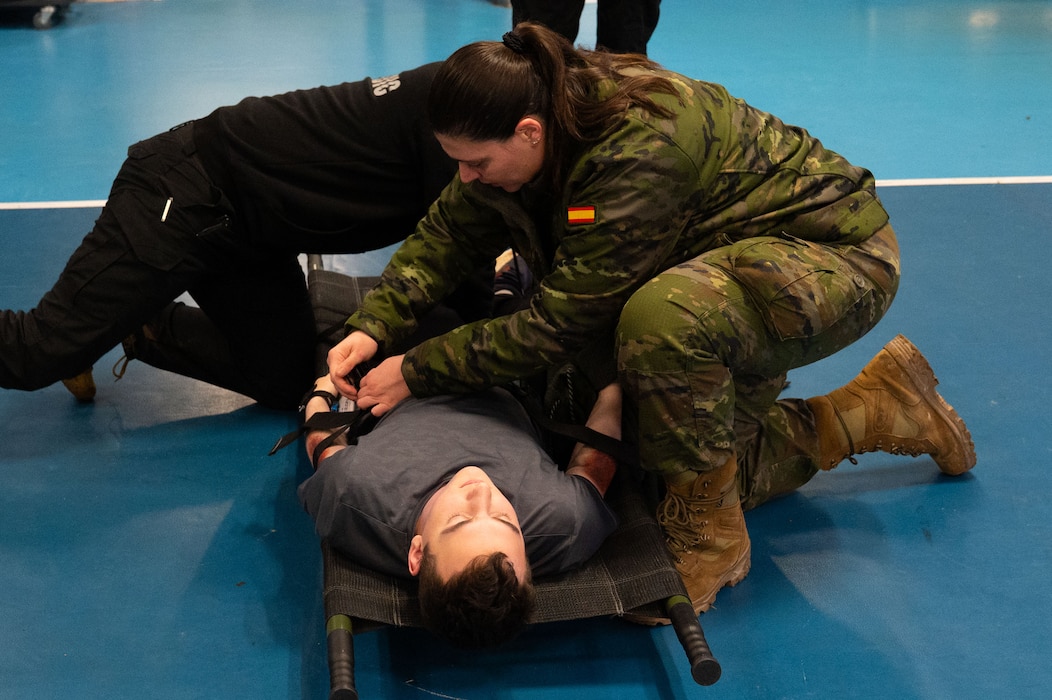 Spanish soldiers prepare simulated victim for transport.