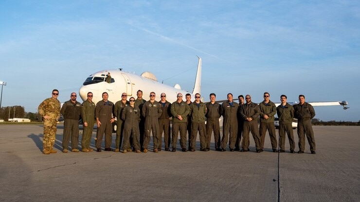 People pose for a photo in front of an aircraft