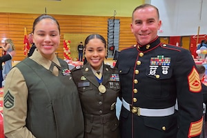 Three service members wearing military dress uniforms smile as they pose for a photo.