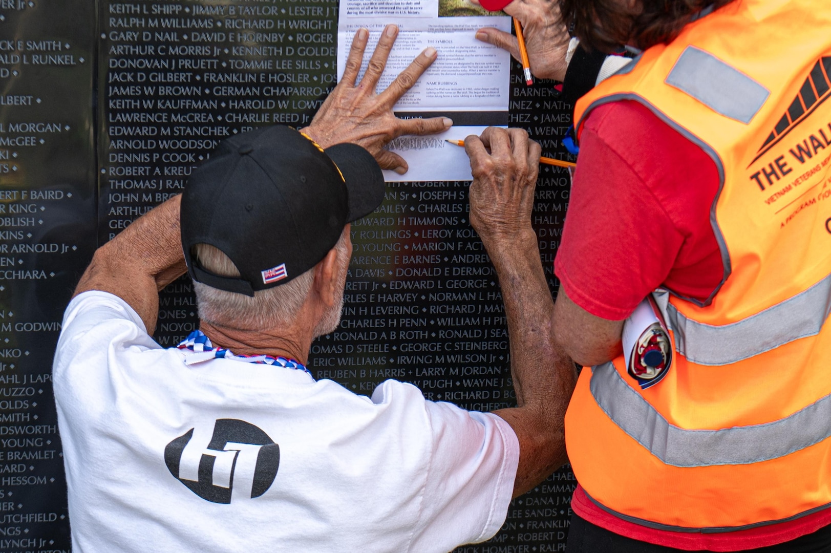 A Vietnam War veteran makes a name rubbing at The Wall That Heals Vietnam Veterans Memorial while assisted by a volunteer at the University of Hawaiʻi – West Oʻahu, Jan. 14.