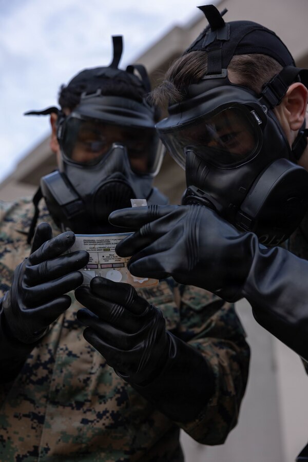 U.S. Marine Corps Lance Cpl. Roger AguilarGarcia, left, a native of San Bernardino, California and Cpl. John Buchner, a native of Bowling Green, Kentucky, both power line mechanics with Marine Aerial Refueler Transport Squadron (VMGR) 152, Marine Aircraft Group 12, 1st Marine Aircraft Wing, identify a type of chemical attack during chemical, biological, radiological, and nuclear training at Marine Corps Air Station, Iwakuni, Japan, Nov. 24, 2025. Marines use the M256A1 kit to detect and identify chemical warfare agents in the field. (U.S. Marine Corps photo by Lance Cpl. Ella Cadby)