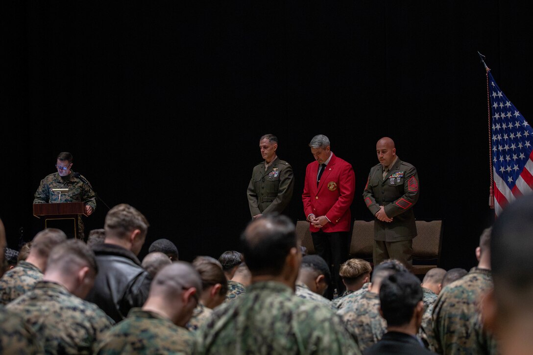U.S. Marines and Sailors from Marine Corps Air Station Iwakuni pray during the Gunnery Sgt. Carlos N. Hathcock Il award ceremony at MCAS Iwakuni, Japan, Nov. 4, 2025. Gunnery Sgt. Robert Navarro was awarded the Gunnery Sgt. Carlos N. Hathcock II award for his prestigious work and dedication to improving marksmanship of the indoor small arms range and efficiently training rifle and pistol qualifications. (U.S. Marine Corps photo by Lance Cpl. Siwan Lewis)