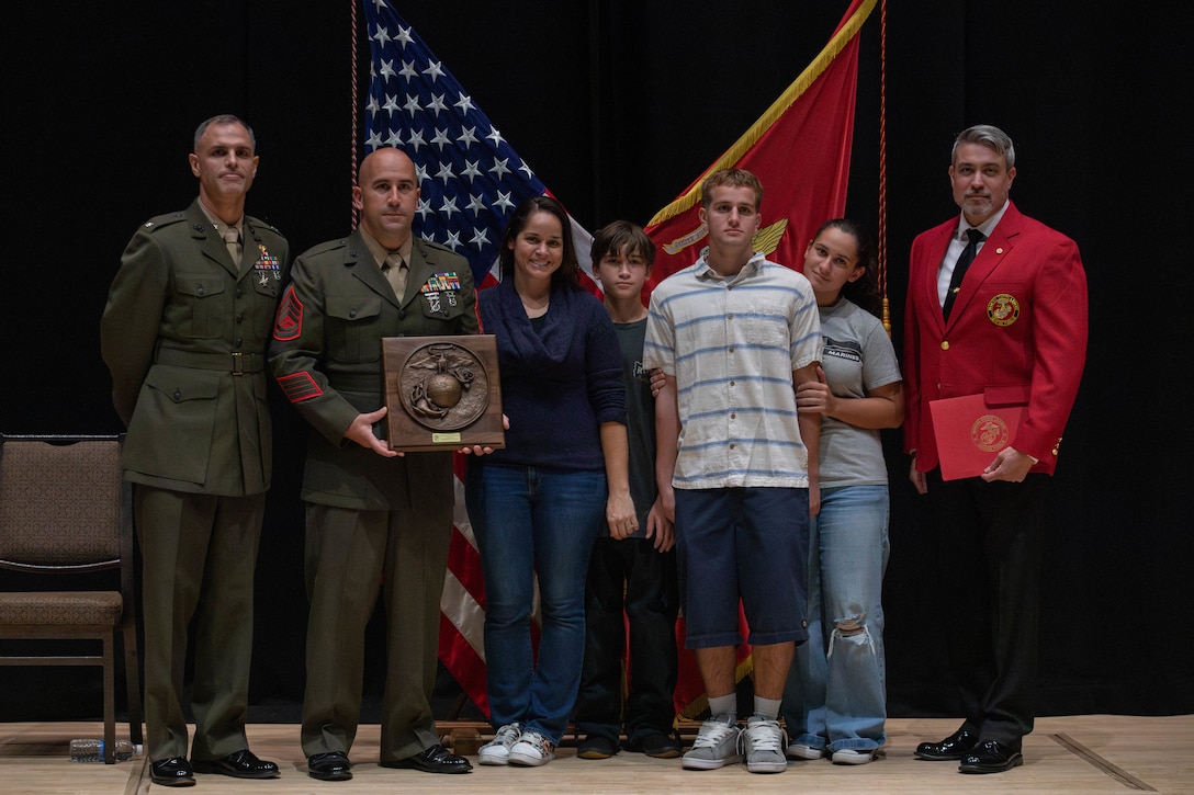 U.S Marine Corps Lt. Col. Federico Mendizabal, left, the commanding officer of Headquarters and Headquarters Squadron (HHS), Marine Corps Air Station Iwakuni, and a New York native, Rob Brooks, right, national director of events with the Marine Corps League, pose for a group photo with award recipient, Gunnery Sgt. Robert Navarro, the officer in charge of the indoor small arms range with HHS, MCAS Iwakuni, native to Oceanside, California, and his family during the Gunnery Sgt, Carlos N, Hathcock II award ceremony at MCAS Iwakuni, Japan, Nov. 4, 2025. Gunnery Sgt. Navarro was awarded the Gunnery Sgt. Carlos N. Hathcock II award for his prestigious work and dedication to improving marksmanship of the indoor small arms range and efficiently training rifle and pistol qualifications. (U.S. Marine Corps photo by Lance Cpl. Siwan Lewis)